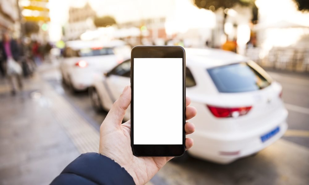 la mano del hombre sosteniendo el telefono movil frente al trafico en la carretera